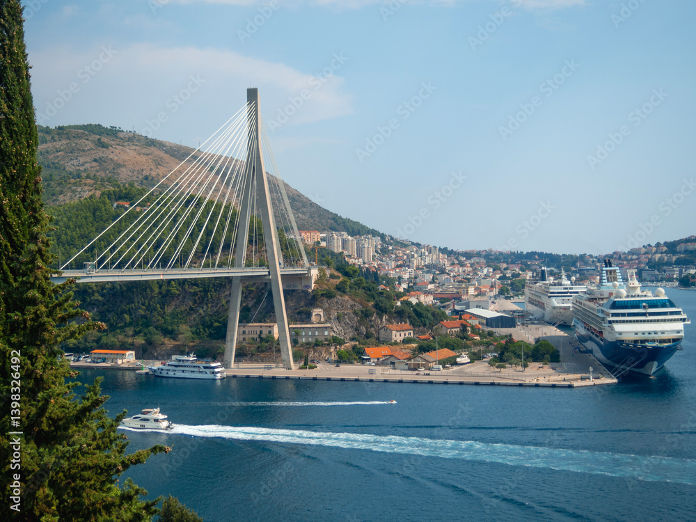Obraz premium View of Dubrovnik harbor with Franjo-Tuđman Bridge suspended in the Adriatic Sea. Panoramic viewpoint where you can admire the scenery of the cruise ships and the bridge