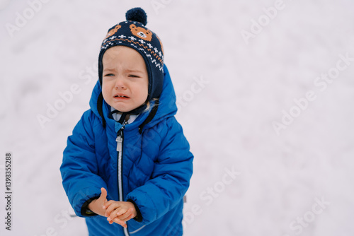 Little girl crying while standing in the snow and holding her hands in front of her