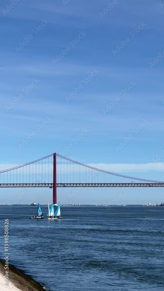 Small sailboats glide on the calm blue water near the red suspension bridge in Lisbon, with the Christ statue in the background under a clear sky. Small sailboats glide on the calm blue water near the red suspension bridge in Lisbon, with the Christ statue in the background under a clear sky.