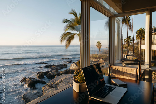 Laptop is open on a desk overlooking the ocean