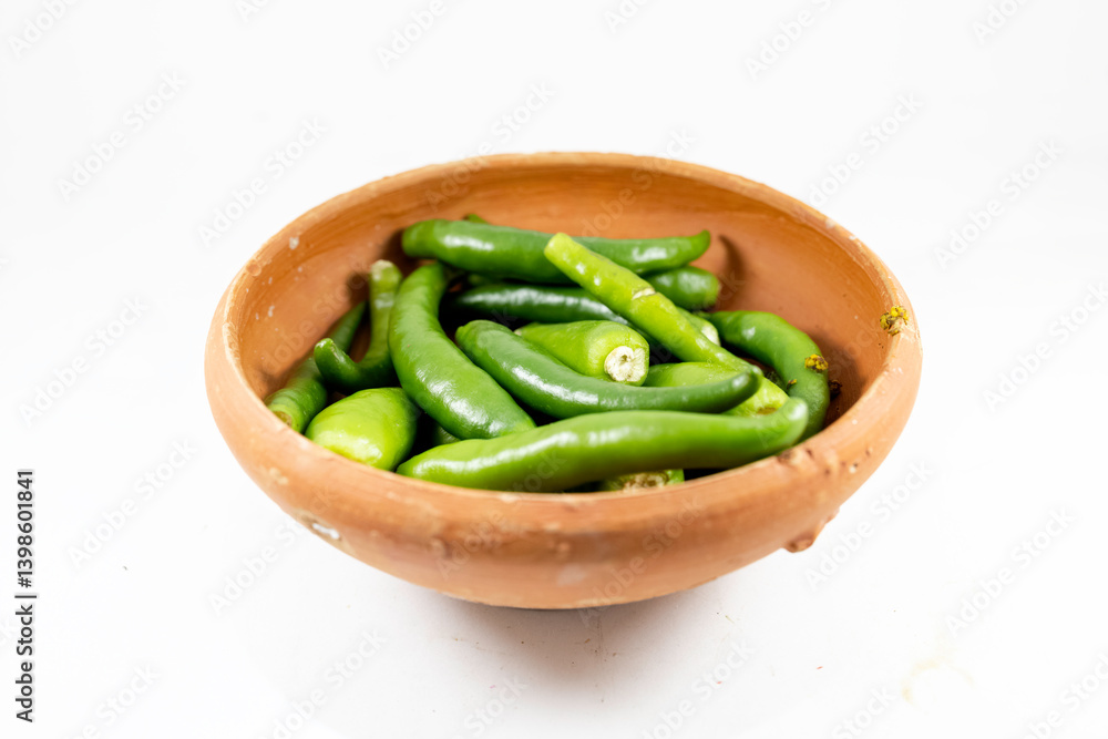 A collection of fresh green chilies displayed in a handmade clay bowl on white background A collection of fresh green chilies displayed in a handmade clay bowl on white background