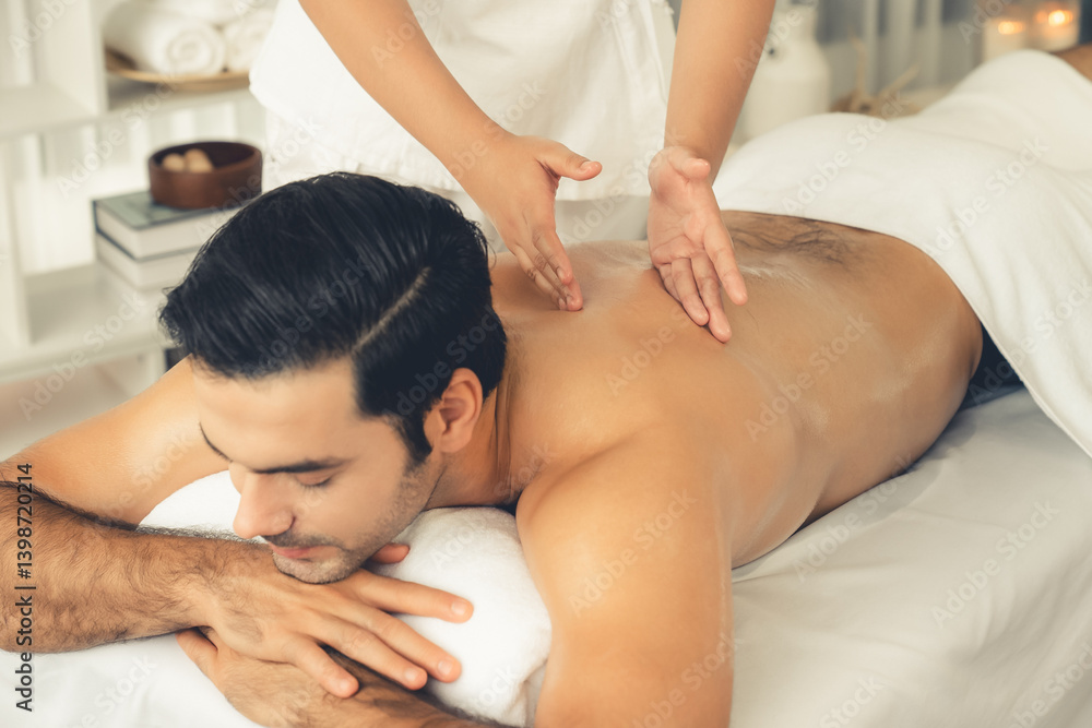 Caucasian man customer enjoying relaxing anti-stress spa massage and pampering with beauty skin recreation leisure in day light ambient salon spa at luxury resort or hotel. Quiescent Caucasian man customer enjoying relaxing anti-stress spa massage and pampering with beauty skin recreation leisure in day light ambient salon spa at luxury resort or hotel. Quiescent