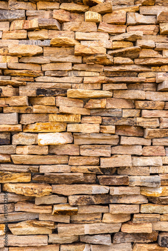 Sandstone wall detail in beige and brown tones, irregularly arranged, creating a rich and natural texture. Ideal for geology, construction, and design concepts