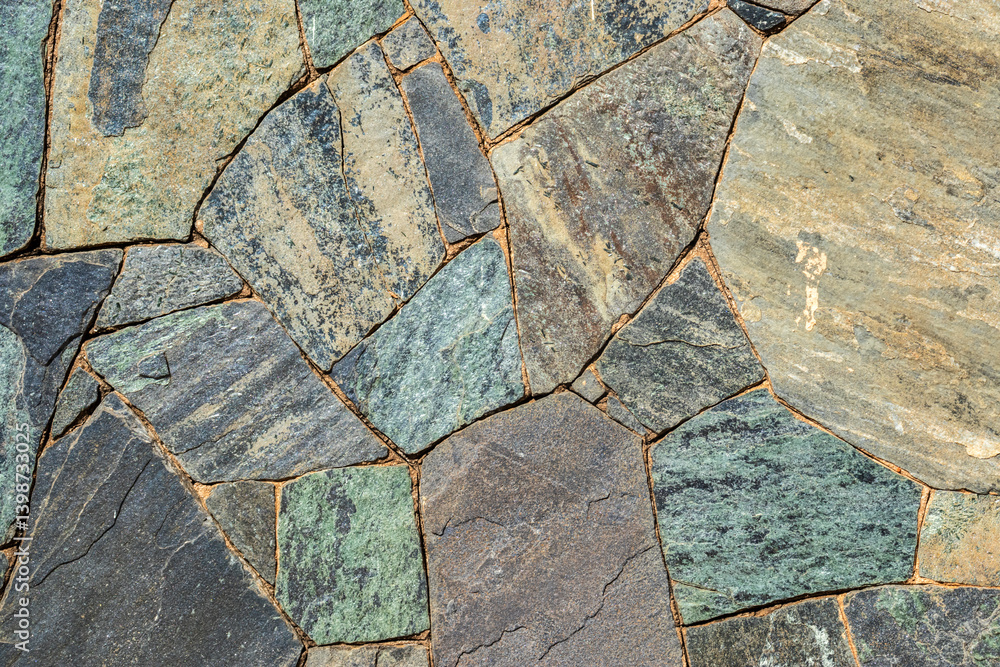 Stone wall detail. Irregular shapes in gray, green and brown tones. Perfect for architecture, geology or landscaping content.