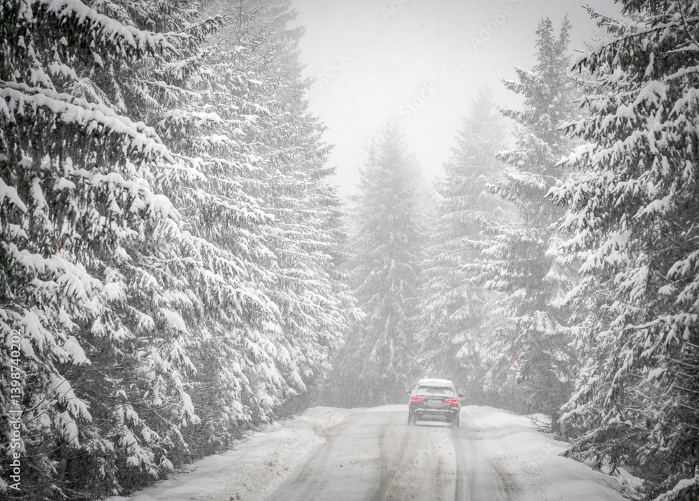 Beautiful winter scene with icy slick road driving car . Alpine road covered with water and ice and snowy trees all around