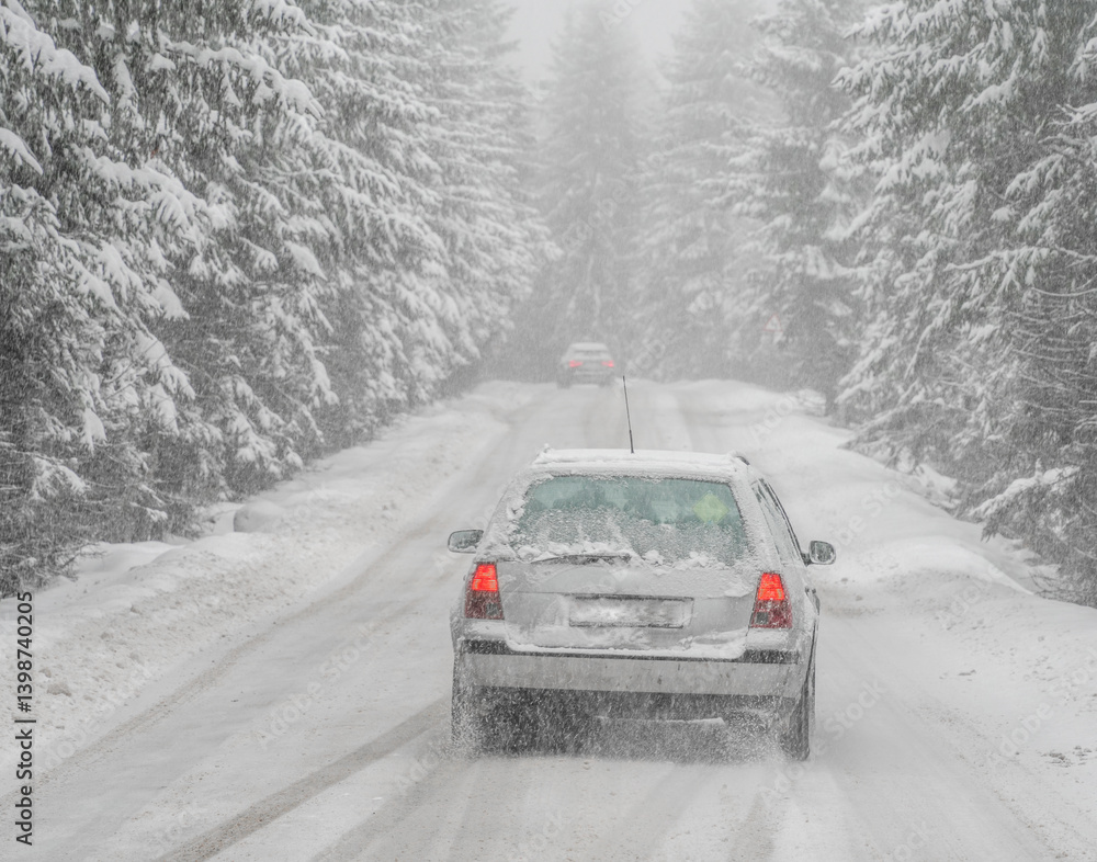 Beautiful winter scene with icy slick road driving car . Alpine road covered with water and ice and snowy trees all around