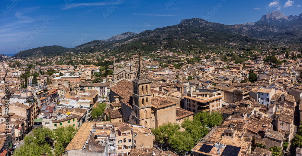 Fototapeta premium Aerial view of the village with parish of Sant Bartomeu in the foreground and the mountains of the Sóller Valley in the background, Sóller, Mallorca, Balearic Islands, Spain