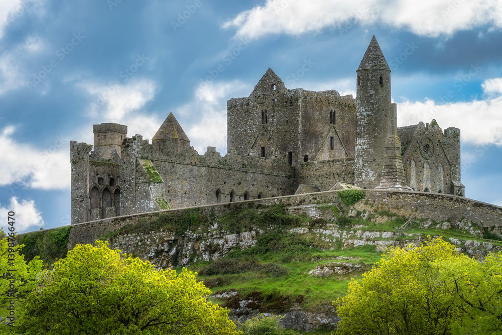 Discover and explore the breathtaking remains of an ancient historic Rock of Cashel castle, beautifully set against a dramatic sky and surrounded by lush greenery and nature, Tipperary, Ireland Discover and explore the breathtaking remains of an ancient historic Rock of Cashel castle, beautifully set against a dramatic sky and surrounded by lush greenery and nature, Tipperary, Ireland