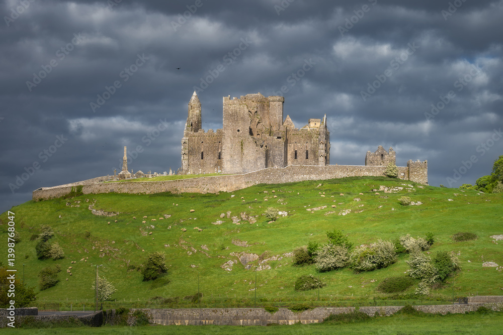 A breathtaking view of magnificent ancient Rock of Cashel ruins, majestically perched on a lush green hillside, enveloped by moody and dramatic clouds ideal for historical themes, Tipperary, Ireland