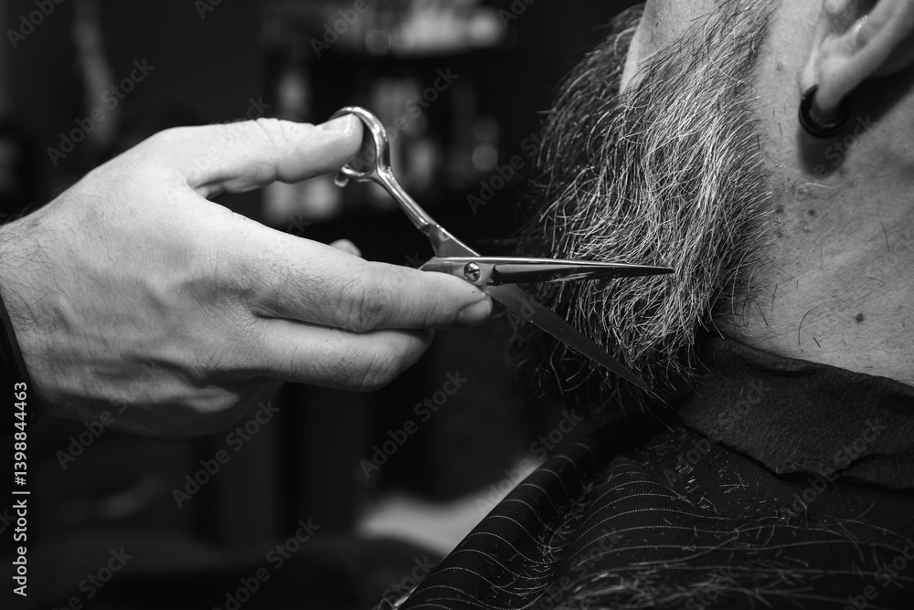 Black and white classic vintage photo, close-up, barber trimming beard with electric clipper, hair scissors in modern barbershop. Professional men's grooming and beard care services, selective focus