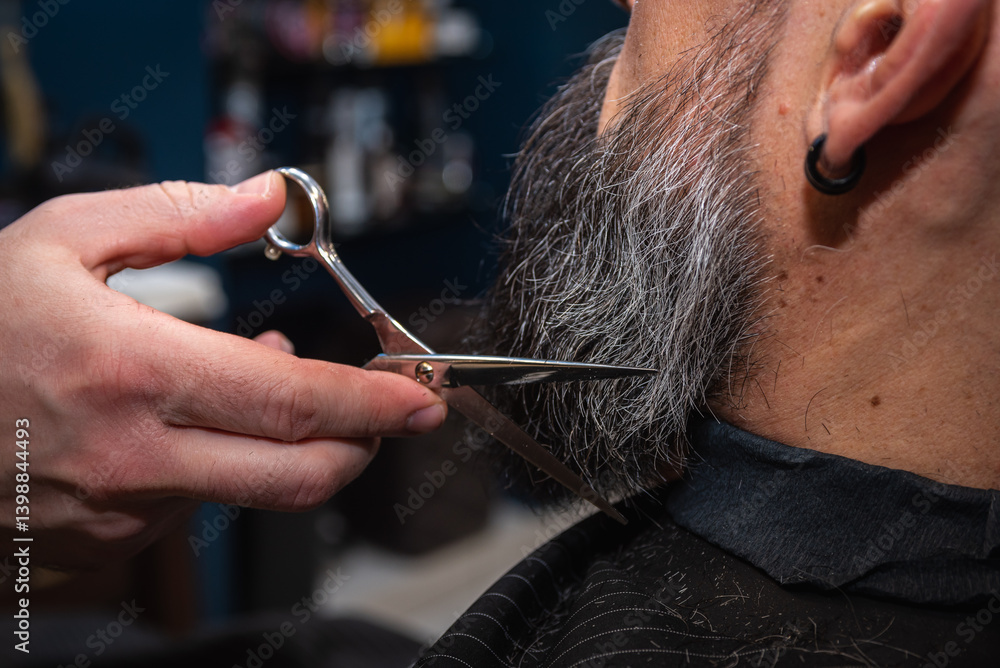 Close-up of a barber trimming a beard with electric clippers in a modern barbershop. Professional men's grooming and beard care service, selective focus