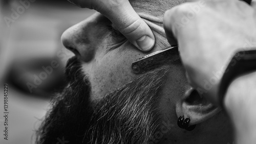 Obraz na płótnie Black and white classic vintage photo, close-up, barber trimming beard with electric clipper, hair scissors in modern barbershop. Professional men's grooming and beard care services, selective focus w salonie