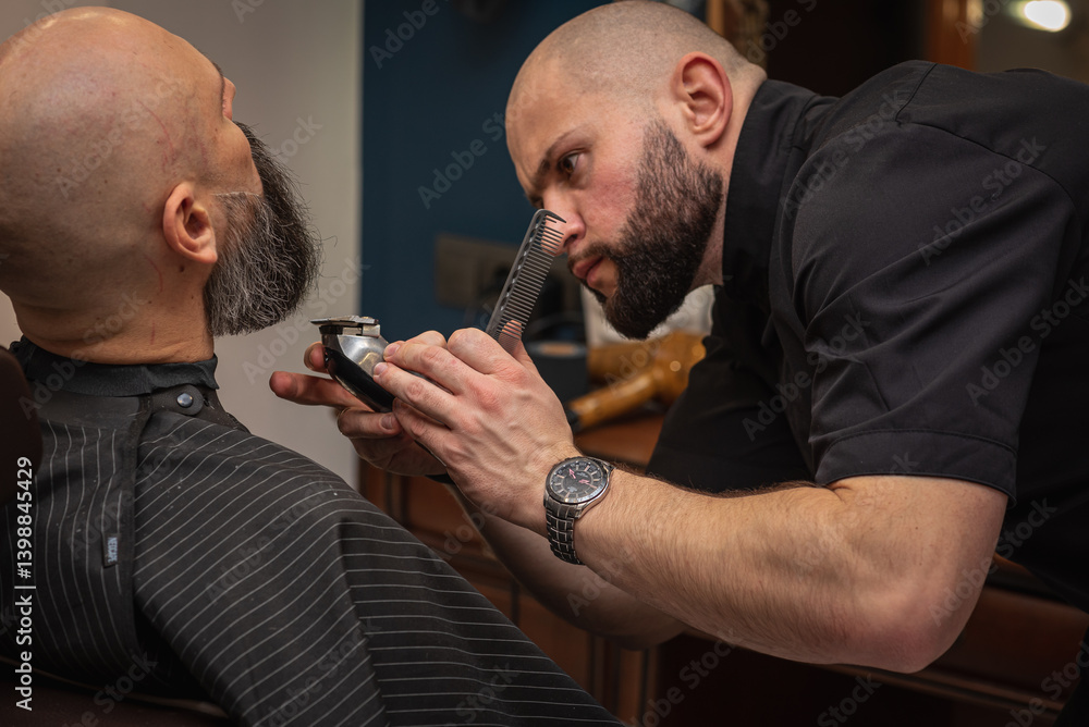 Close-up of a barber trimming a beard with electric clippers in a modern barbershop. Professional men's grooming and beard care, selective focus