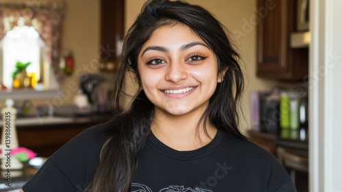 Free Download A woman with long hair is smiling and wearing a black shirt with a heart on it. She is standing in a kitchen - GFXLoad