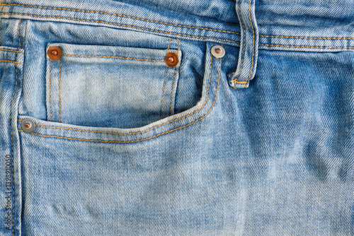 Closeup of a small watch pocket with copper rivets of a worn blue denim jeans trousers	