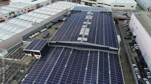 Aerial view of solar panels providing clean energy on a factory roof, promoting sustainability and reducing carbon footprint