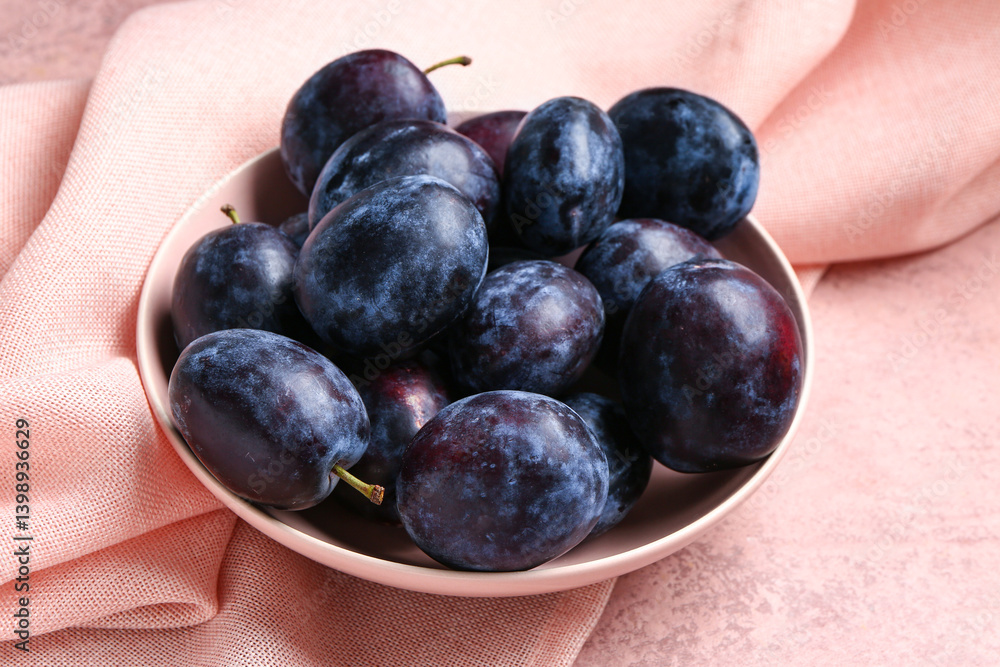 Fototapeta premium Bowl with fresh plums on pink background