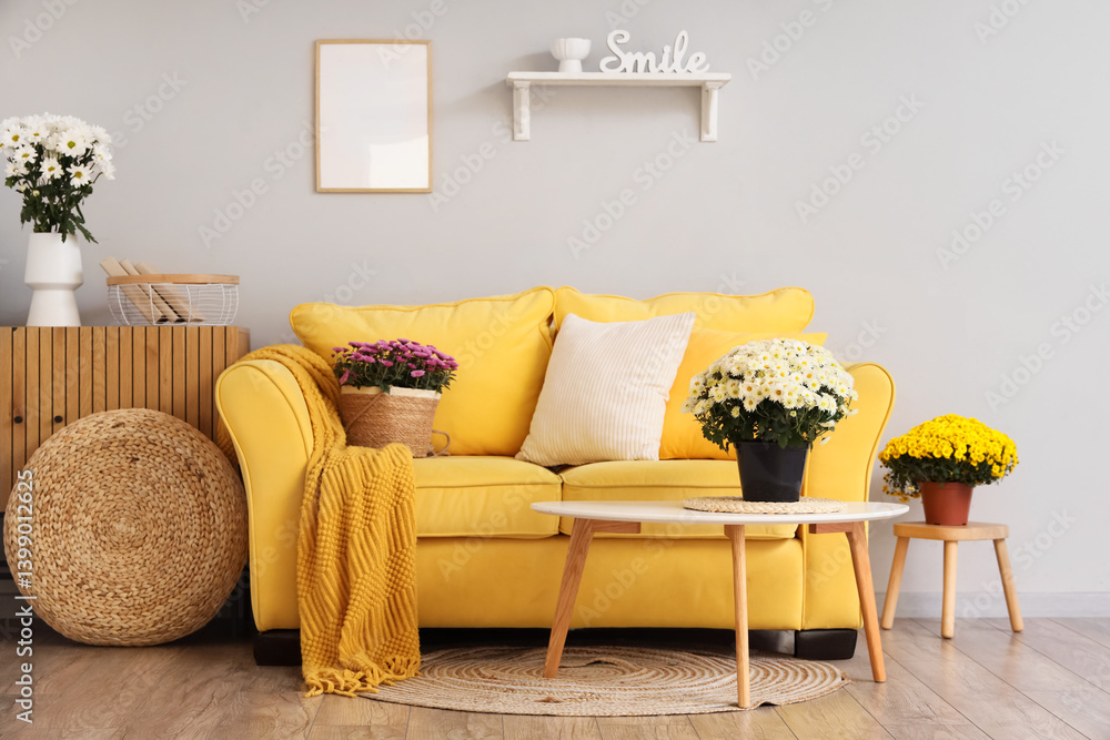 Interior of living room with yellow sofa, drawers and chrysanthemum flowers