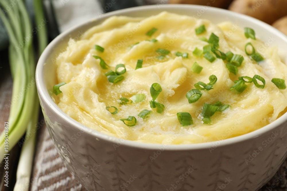 Tasty mashed potato with green onion in bowl on wooden table, closeup Tasty mashed potato with green onion in bowl on wooden table, closeup