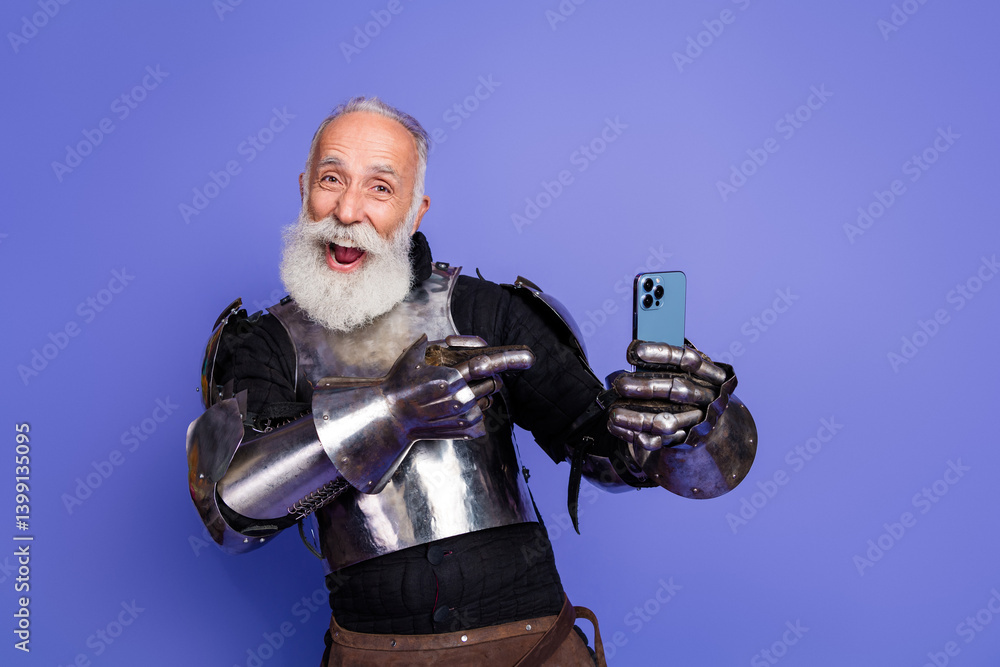 Naklejka premium Elderly knight in full armor joyfully posing with a smartphone against a purple backdrop