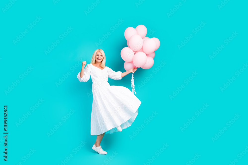 Cheerful woman in a white dress holding pink balloons against a vibrant turquoise background Cheerful woman in a white dress holding pink balloons against a vibrant turquoise background