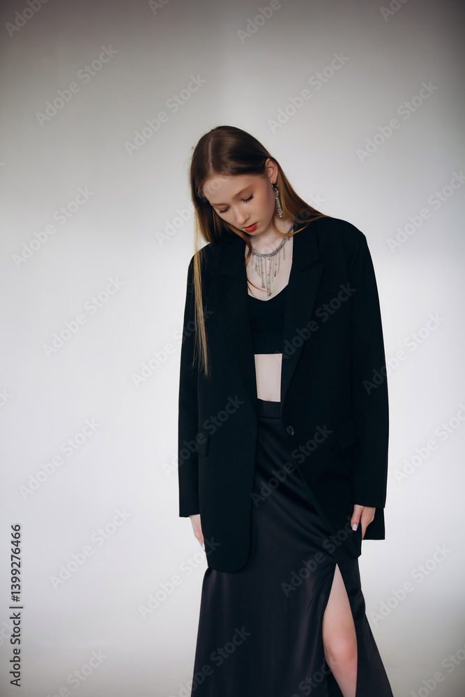 Fototapeta premium Beautiful blonde model, young girl, teenager in the studio in a black jacket on a white cyclorama