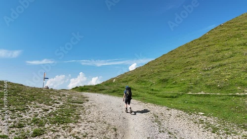 Male hiker (man) with trekking backpack hiking on path towards Mont Blanc massif mountain panorama in Western Alps, France 