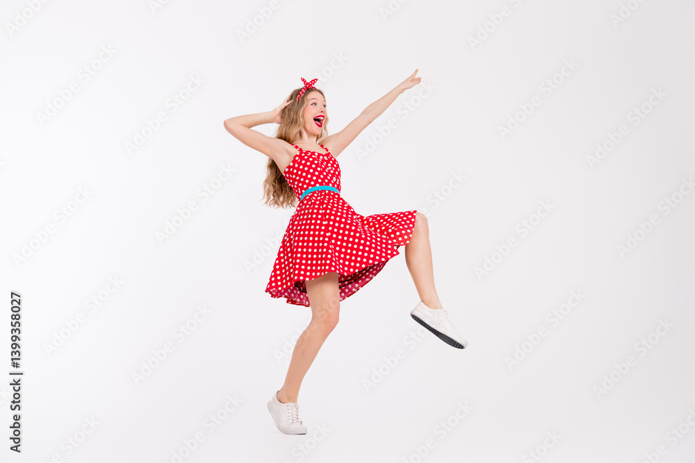 Cheerful young woman dancing in a vintage red polka dot dress, showcasing retro style and vibrant energy on a white background