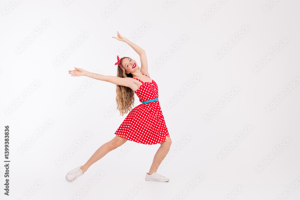 Young woman in a red polka dot dress posing dynamically, expressing joy, nostalgia, and vibrant retro vibes against a white background. Young woman in a red polka dot dress posing dynamically, expressing joy, nostalgia, and vibrant retro vibes against a white background.