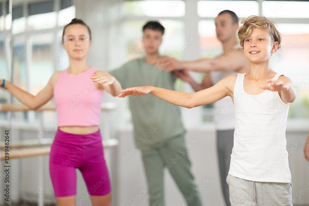 In dance studio, teen boy in group lesson with students rehearses, practices ballet dance, staging.