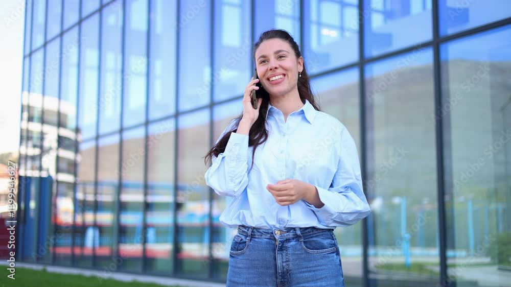 Young businesswoman smiling while talking on a mobile phone in front of an office building Young businesswoman smiling while talking on a mobile phone in front of an office building