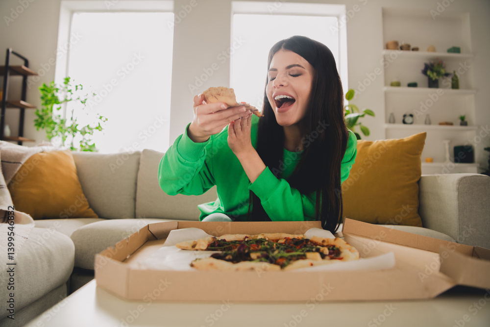 Young woman in a green pullover enjoying pizza indoors in a modern living room, showcasing a cheerful moment Young woman in a green pullover enjoying pizza indoors in a modern living room, showcasing a cheerful moment