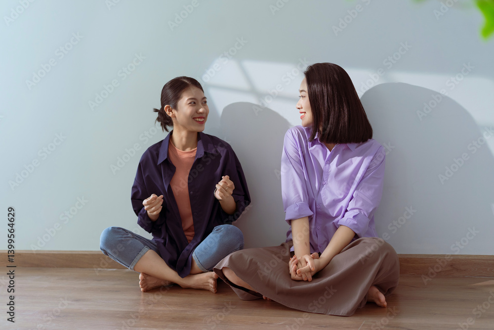 Two friends enjoying a cheerful conversation in a bright, minimalistic room during a sunny afternoon Two friends enjoying a cheerful conversation in a bright, minimalistic room during a sunny afternoon