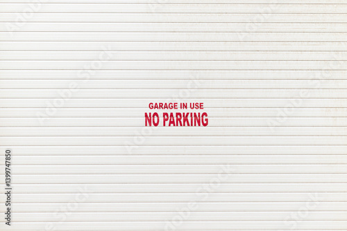 White garage door with a notice - garage in use no parking