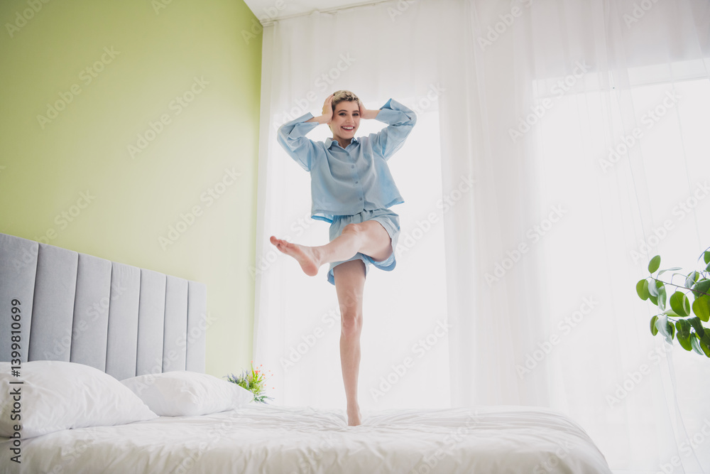 Young woman in sleepwear smiling and enjoying a relaxing moment in a cozy bedroom during a bright morning indoors Young woman in sleepwear smiling and enjoying a relaxing moment in a cozy bedroom during a bright morning indoors