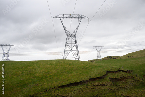 High voltage power pylon and power cables on rolling green hills. North Island. New Zealand.