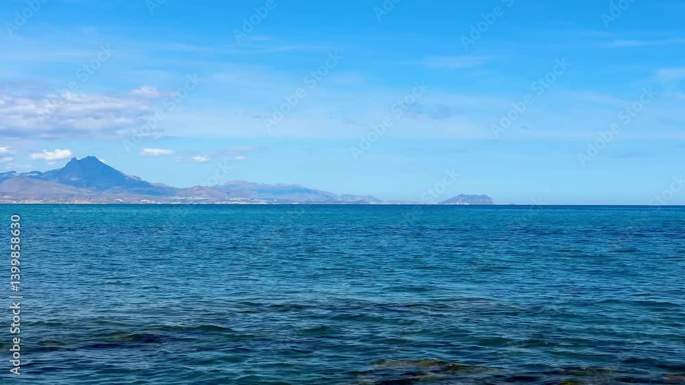 A stunning and beautiful coastal view showcasing the vast ocean, distant majestic mountains, and a clear blue sky A stunning and beautiful coastal view showcasing the vast ocean, distant majestic mountains, and a clear blue sky
