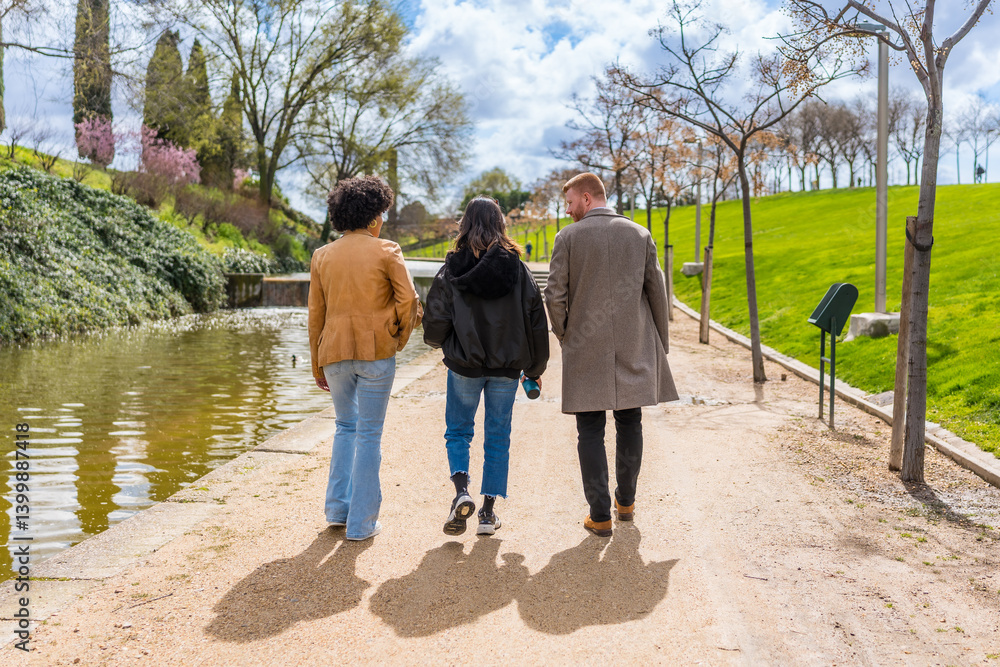 Friends walking along canal in city park during spring