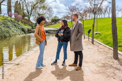 Obraz na płótnie Three young professionals chatting by the canal in a park w salonie
