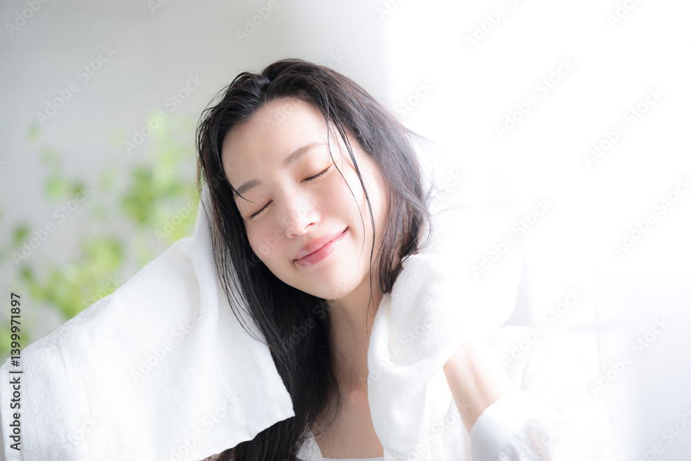 Woman towel drying wet hair in the morning or after a bath by a backlit window Close your eyes Woman towel drying wet hair in the morning or after a bath by a backlit window Close your eyes