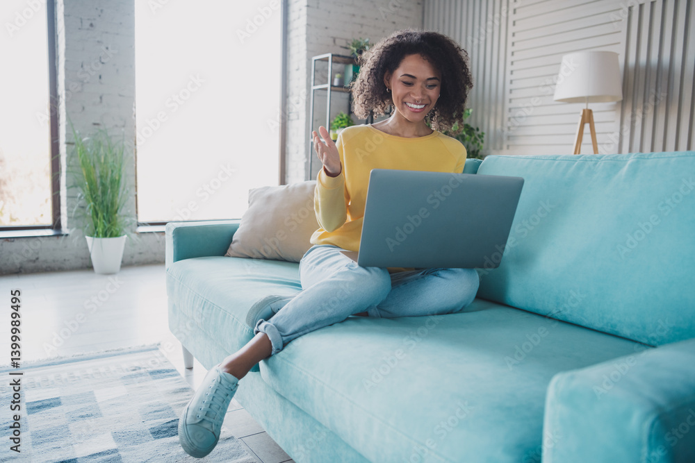 Fototapeta premium Young woman relaxing on a couch while using a laptop in a cozy and modern interior