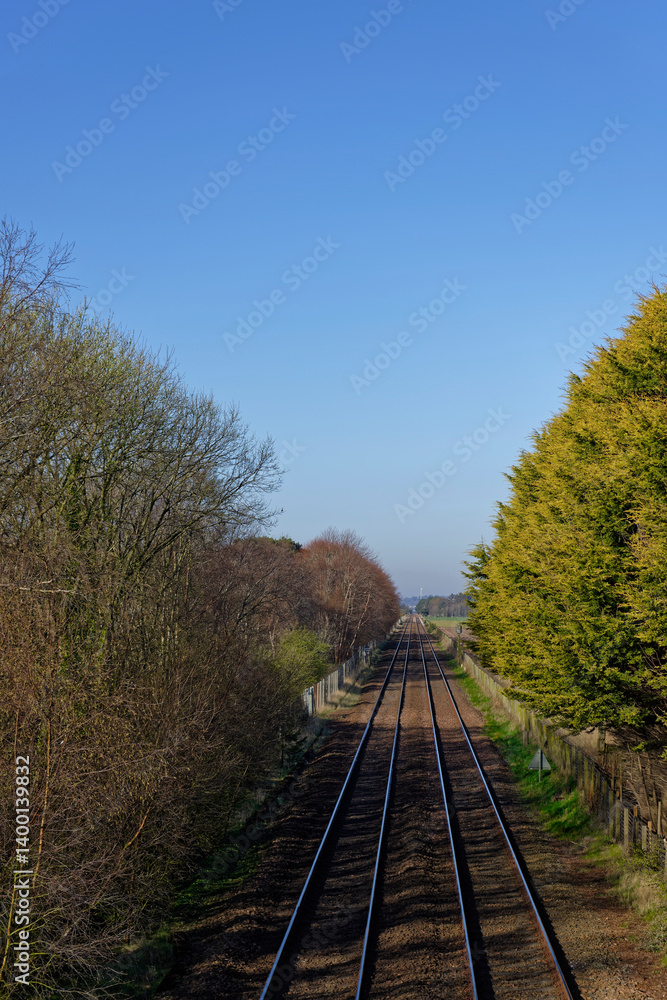 Fototapeta premium The East Coast Main Rail Line passing by Barry Links Station between the farm fields of this rural coastal location on a sunny day in April.