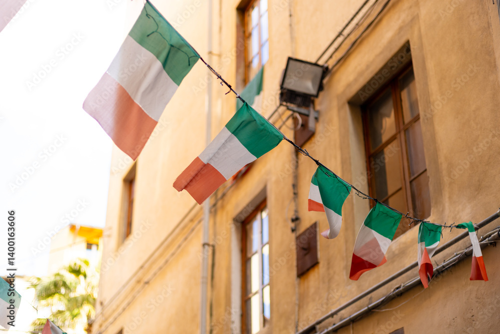 Typical street with houses in Italy. Facade of a yellow building with Italian flags. Italian flag in an old town narrow street of a city in Italy