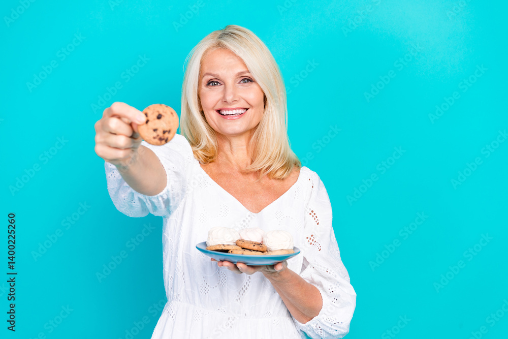 Smiling elderly woman showing a cookie with a stylish blue background, embodying happiness, charm, and leisure in a summery casual fashion. Smiling elderly woman showing a cookie with a stylish blue background, embodying happiness, charm, and leisure in a summery casual fashion.