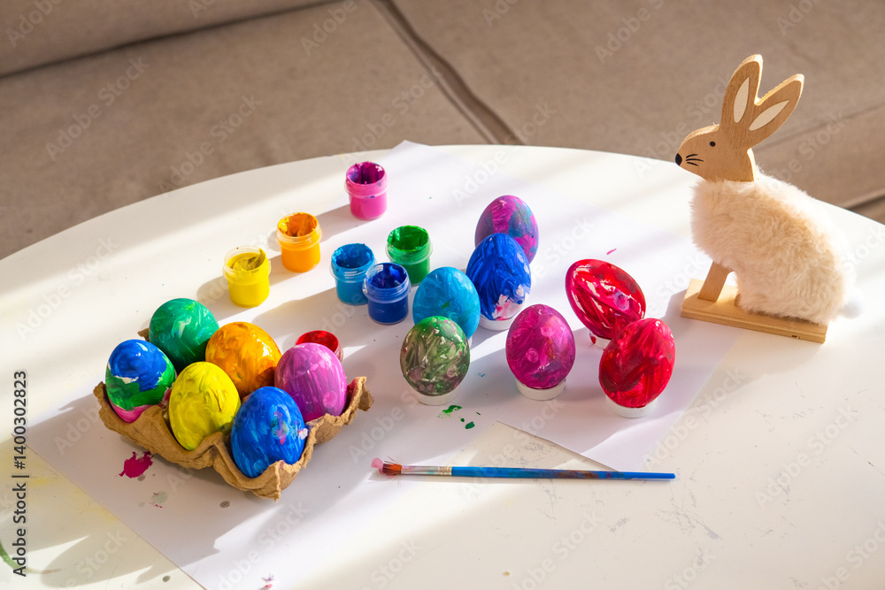 Colorful Easter egg decorating activity on a bright table with a bunny decoration