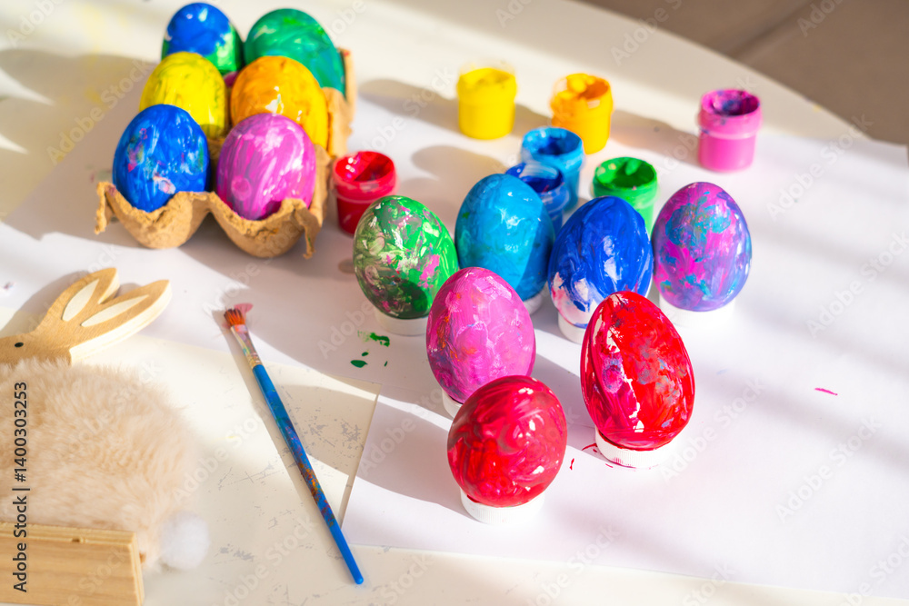 Brightly colored Easter eggs and painting supplies arranged on a table in a warm, sunlit room during a spring afternoon