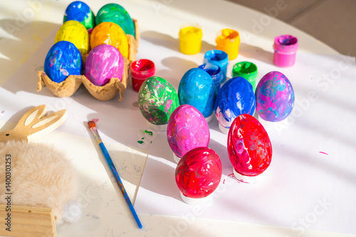 Obraz na płótnie Brightly colored Easter eggs and painting supplies arranged on a table in a warm, sunlit room during a spring afternoon w salonie