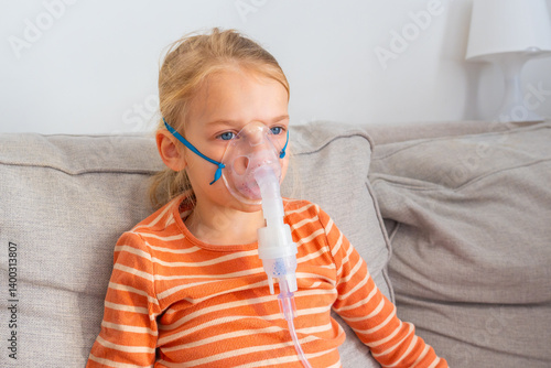 Young girl using a nebulizer at home while sitting on a couch in a relaxed atmosphere