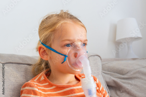 Obraz na płótnie Young girl receives respiratory treatment at home while sitting comfortably on a couch during a sunny afternoon w salonie