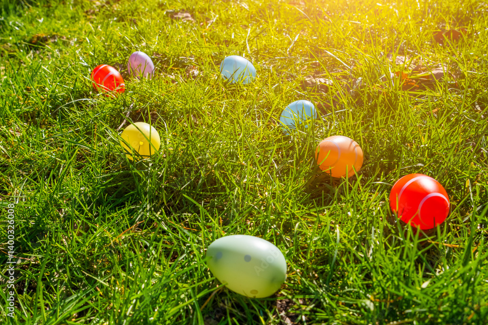 Colorful Easter eggs scattered on green grass during a sunny spring day in the park